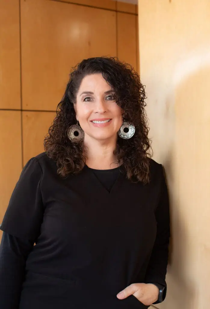 a woman with curly hair wearing large earrings