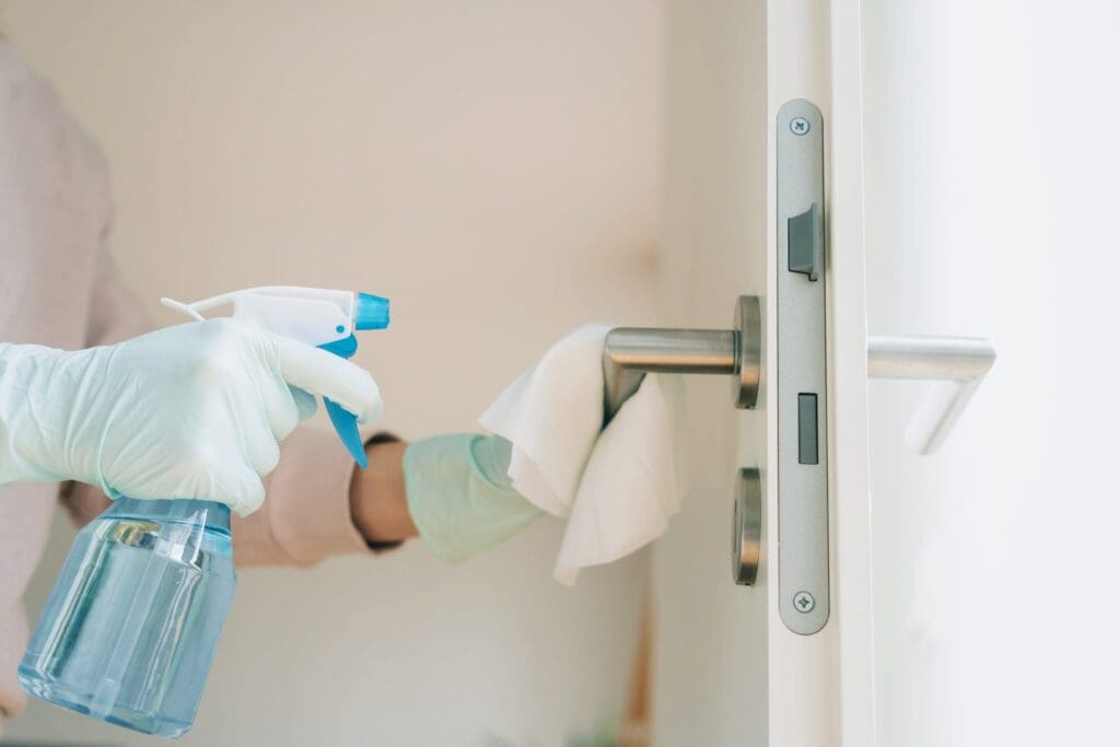 Woman cleaning a door handle with a disinfection spray Woman cleaning a door handle with a disinfection spray