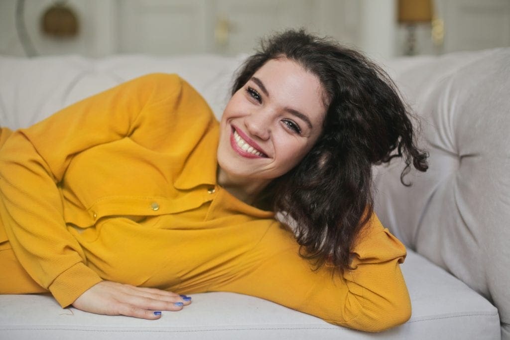 Woman in a yellow gold shirt on the couch