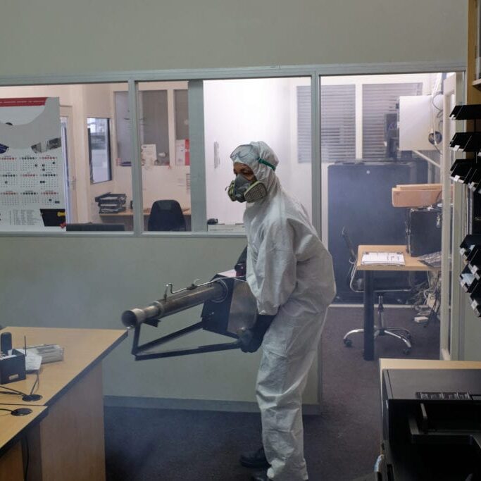 A man dressed in full protective gear uses an industrial fogging machine to spray and disinfect an entire office space. Sanitization/fogging to help stop the spread of the Coronavirus, Cape Town.